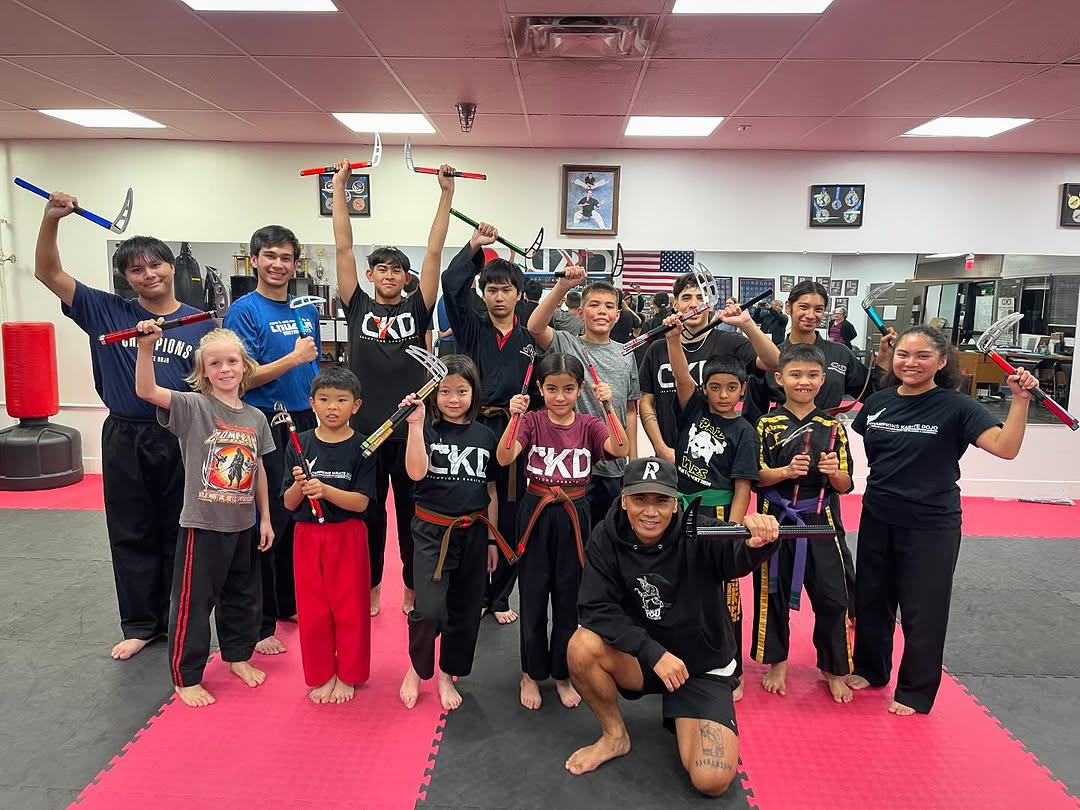 Rudy Reynon II leading a kamas workshop — students holding kamas overhead