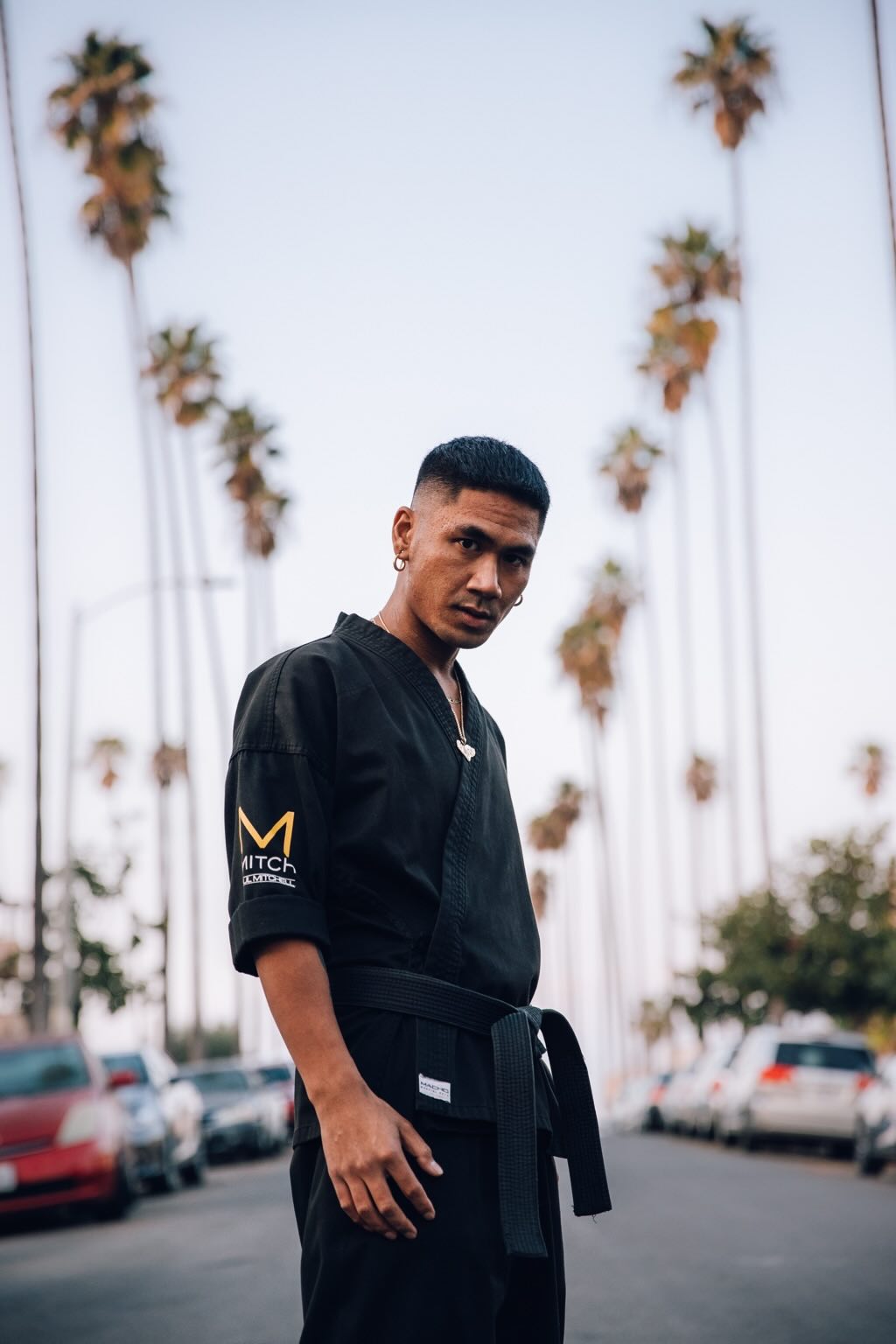 Rudy Reynon II in black gi, palm tree street — martial arts portrait
